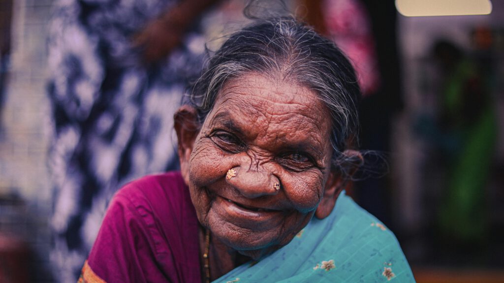 Portrait of a smiling elderly woman wearing a sari, highlighting cultural and traditional Indian attire.